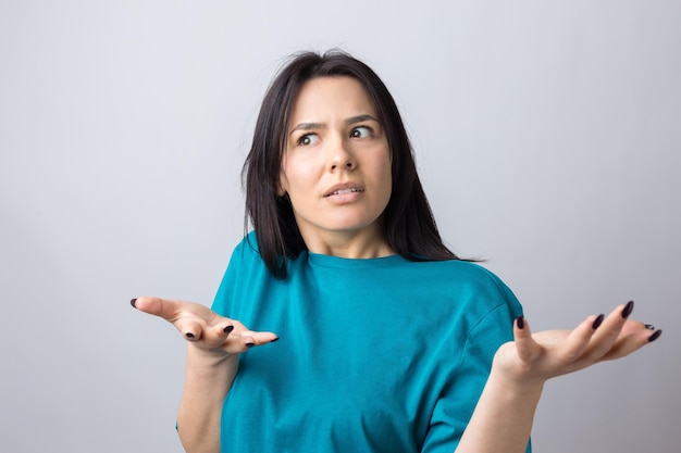 Young beautiful woman with facial expression of surprise standing over gray background.