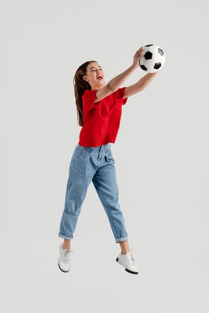 Young beautiful woman with football ball jumping