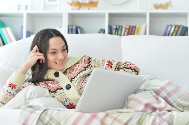 Young beautiful woman with laptop on sofa