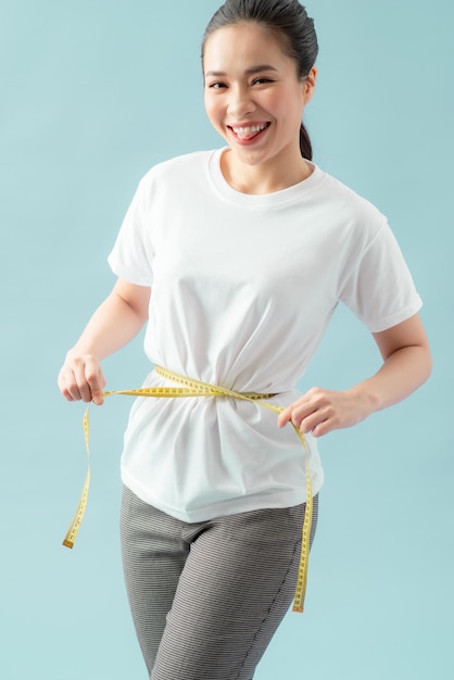 Young beautiful woman with measure tape on blue