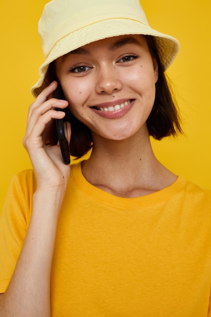 Young beautiful woman yellow tshirt and Hat summer style with phone Lifestyle unaltered