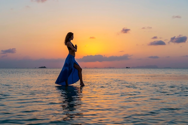 Young beauty girl dancing at tropical beach on sea water at paradise island at sunset close up Summer concept Holiday travel