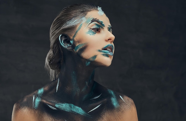 Young beauty girl with creative make-up. Blue and black shadows painted on her face. Conceptual idea.