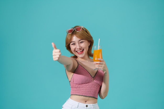 Young beauty in summer Woman with sunglasses drinks orange juice in summer showing thumb up