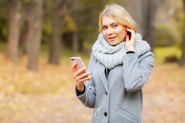 Young Beauty woman listening music in autumn forest