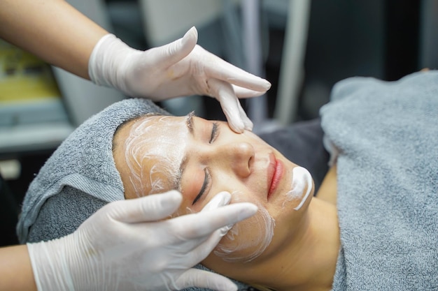 Young beauty woman in towel making facial massage with organic face scrub