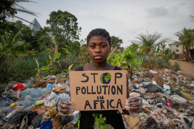 Young black african girl holding a sign written stop pollution in Africa