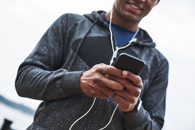 The young black athlete is listening to music after training in the city