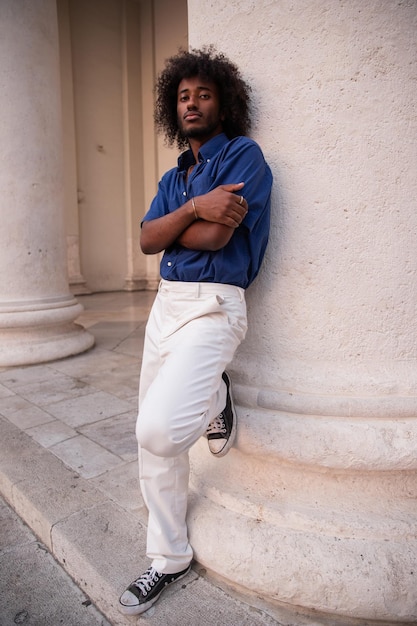 Young black boy leaning against a column in downtown looks thoughtfully ahead