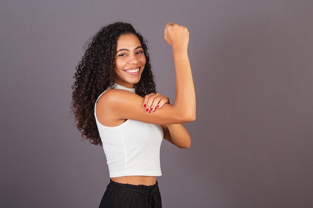 Young black Brazilian woman with raised and closed fist militancy feminism Smiling