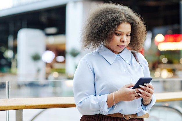 Young Black Businesswoman using Phone in Mall