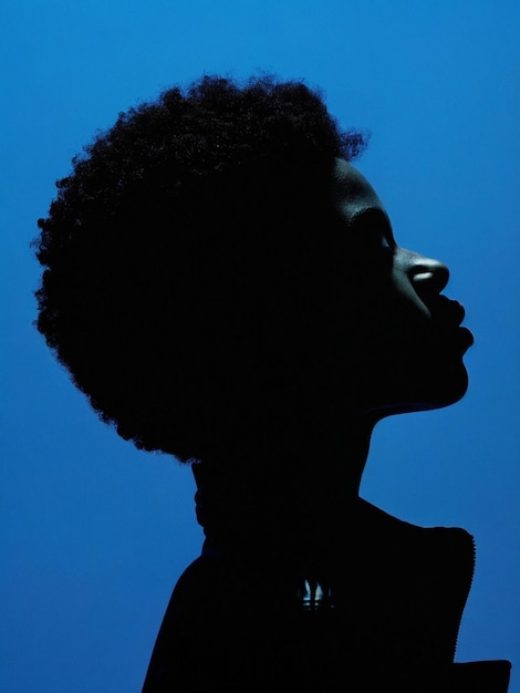 Photo a young black girl with curly hair looking up at the sky she is wearing a black jacket silhouette portrait