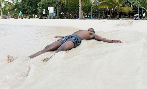 Young black guy laying on the sand