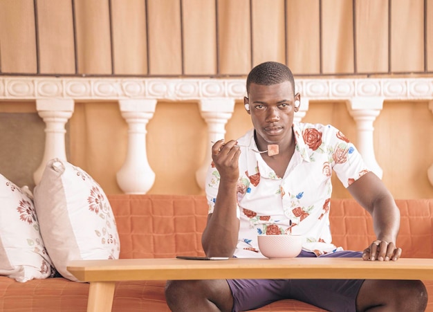 Young black man smiling while listening to music sitting and eating watermelon