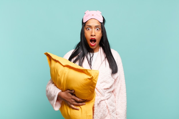 Young black woman looking very shocked or surprised, staring with open mouth saying wow. pajamas concept