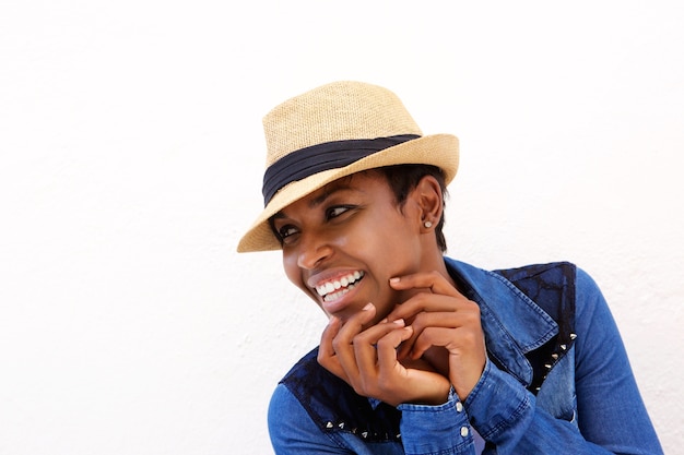 Young black woman smiling against white background with hat