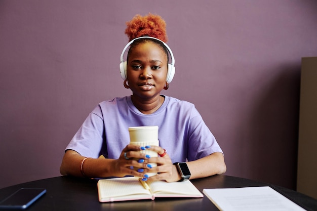 Young black woman wearing headphones in purple interior