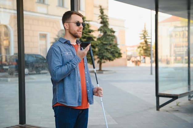 Photo young blinded man using phone and sending voice message