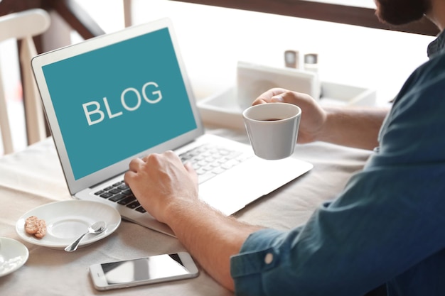 Photo young blogger drinking coffee and using laptop in cafe