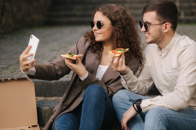 Young bloggers make selfie with slice of pizza in hands