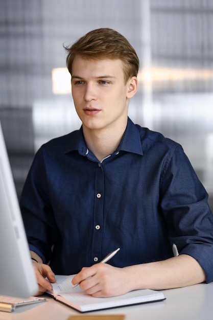 Young blond businessman working with computer. Startup business means working hard and out of time for success achievement.