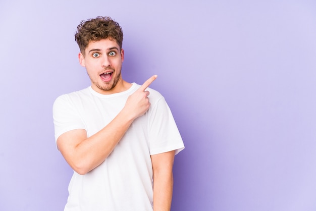 Young blond curly hair caucasian man isolated pointing to the side