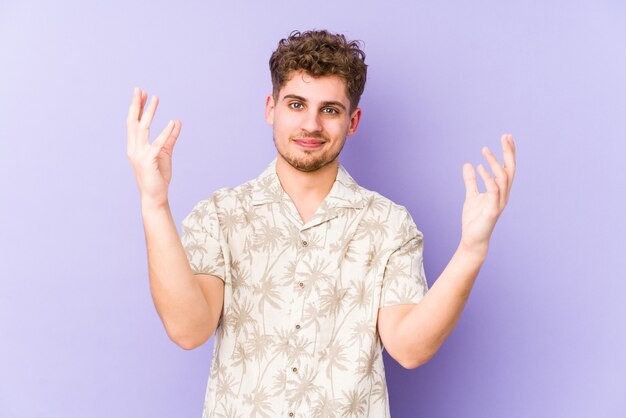 Young blond curly hair caucasian man isolated receiving a pleasant surprise, excited and raising hands.