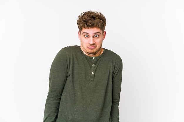 Photo young blond curly hair caucasian man isolated shrugs shoulders and open eyes confused.