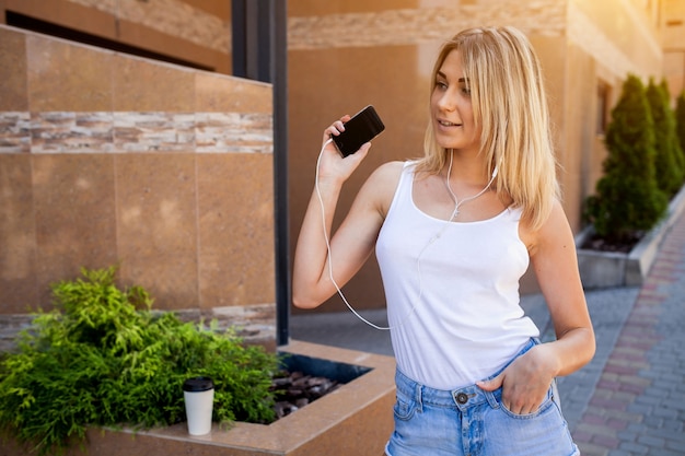 Young blond girl listening to music on her smartphone