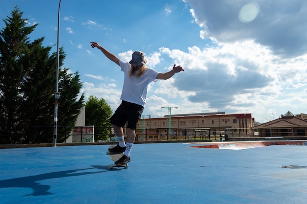 Young blond guy performing skateboarding tricks jumping in the skatepark