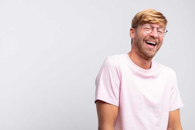 Young blond man happy and smiling isolated