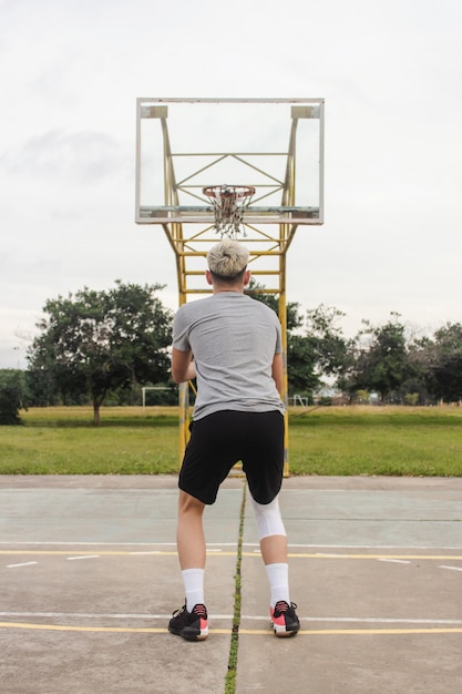 Young blond man preparing to shoot on an abandoned basketball court.