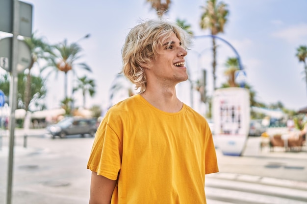 Young blond man smiling confident looking to the side at street