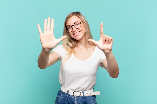 Young blond pretty woman smiling and looking friendly, showing number seven or seventh with hand forward, counting down