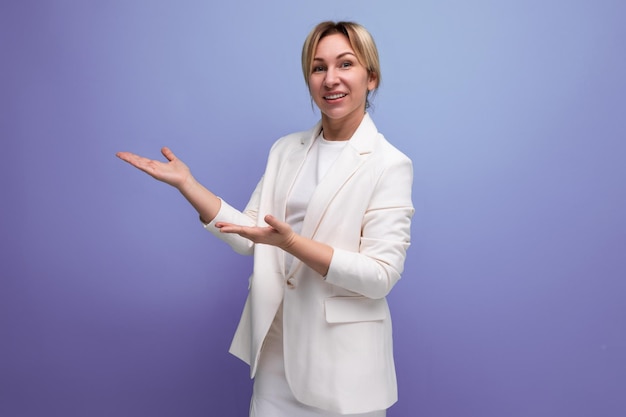 Young blond woman dressed in a jacket and dress demonstrates with her hands an advertising offer