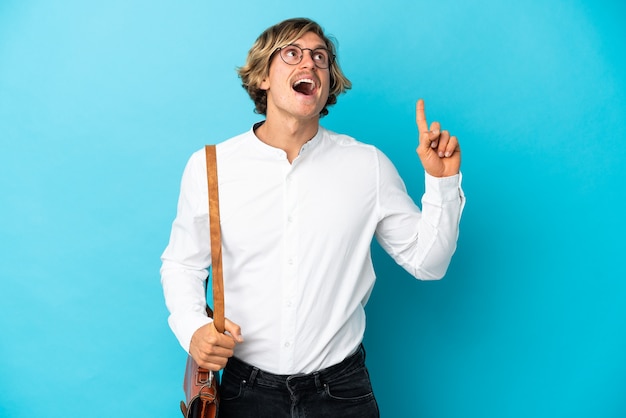 Young blonde businessman isolated on blue wall intending to realizes the solution while lifting a finger up