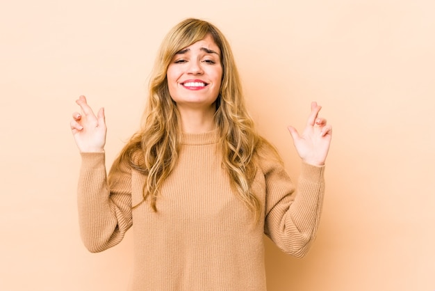 Photo young blonde caucasian woman crossing fingers for having luck