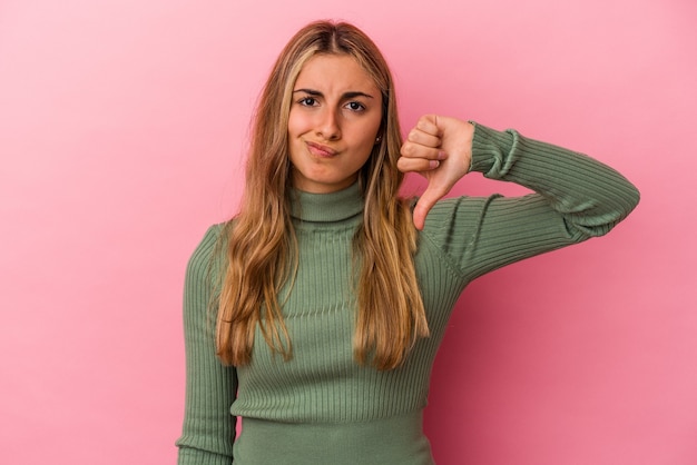 Young blonde caucasian woman isolated on pink background showing thumb down, disappointment concept.