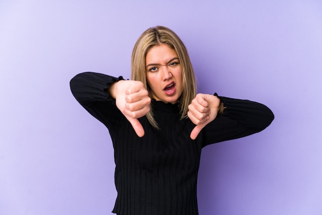 Young blonde caucasian woman isolated showing thumb down and expressing dislike.