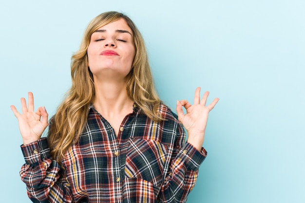 Young blonde caucasian woman relaxes after hard working day, she is performing yoga.