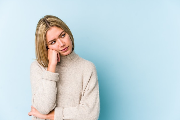 Young blonde caucasian woman who feels sad and pensive, looking at blank space.