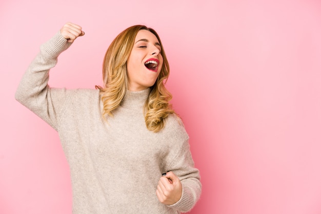 Young blonde cute woman wearing a sweater isolated raising fist after a victory, winner concept.