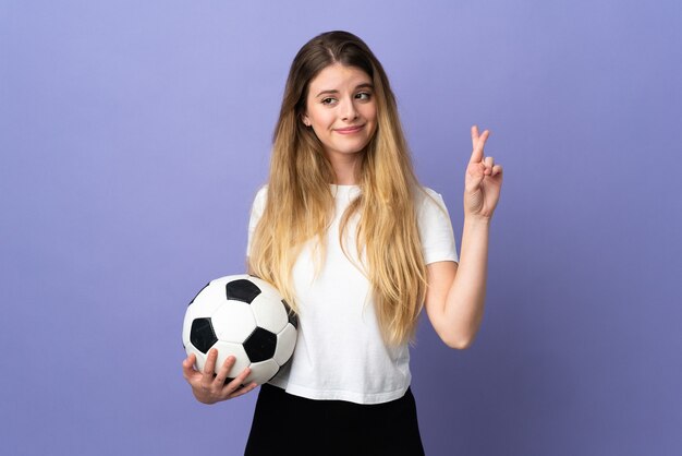 Young blonde football player woman isolated with fingers crossing and wishing the best