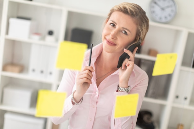 A young blonde girl is standing in the office next to a transparent board with stickers