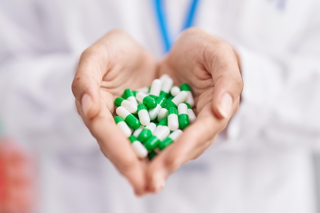 Young blonde girl pharmacist smiling confident holding capsules at pharmacy