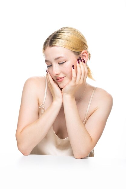 Photo a young blonde girl with freckles in a golden top beauty portrait of a woman on a white background in the studio