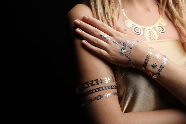 Young blonde girl with golden and silver flash tattoo on black background