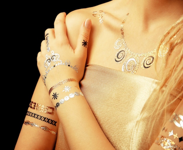 Young blonde girl with golden and silver flash tattoo on black background