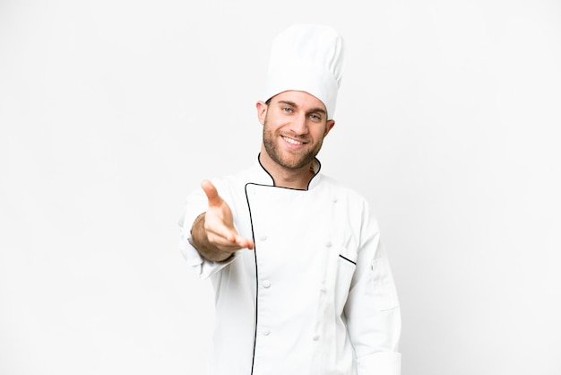 Young blonde man Chef over isolated white background shaking hands for closing a good deal