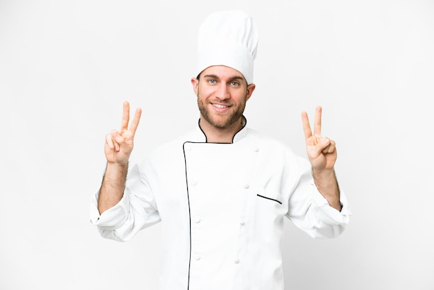 Young blonde man Chef over isolated white background showing victory sign with both hands